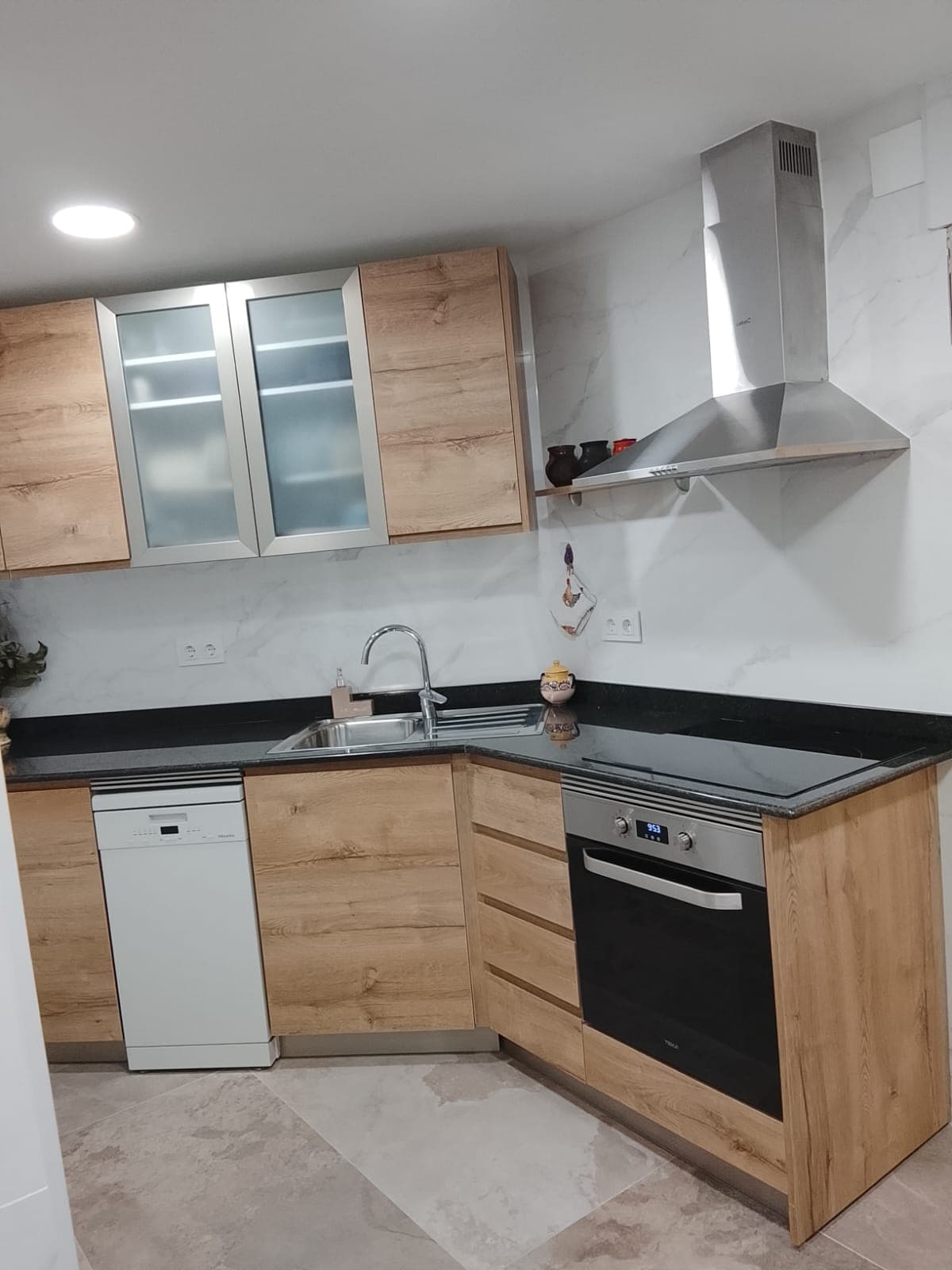 Cocina reformada con encimera de granito y campana extractora